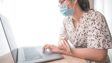 Close up low angle view of Woman in quarantine for Coronavirus wearing protective mask and smart working Hands holding credit card and using laptop. Online shopping