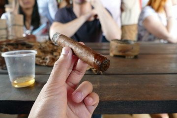 Cigar completed and smoking, accompanied with a cup of liquor
