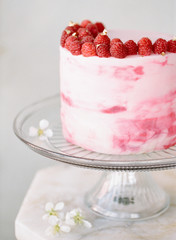 A close up of a one tier cake garnished with raspberries