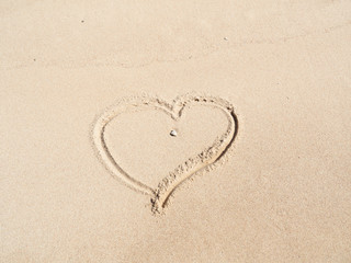 Heart drawn by finger on yellow sand, close up view. Photographed in egyptian beach in february. Yellow sand background