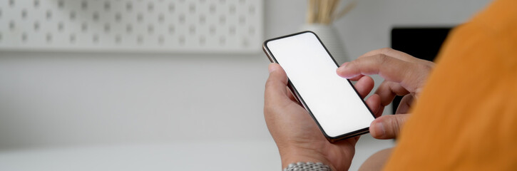 Cropped shot of male freelancer touching on mock-up smartphone at home office