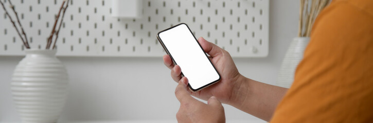 Close up view of male freelancer touching on mock-up smartphone at home office