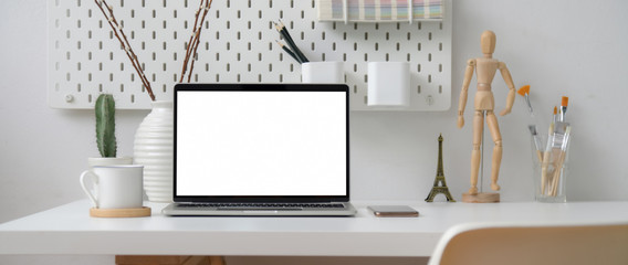 Close up view of home office with blank screen laptop, decorations and supplies