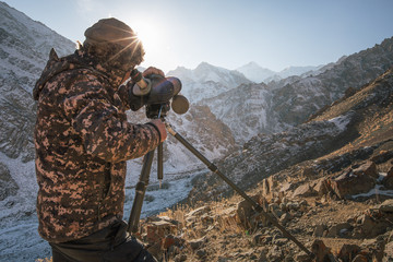 Spotter looking through a scope for snow leopards and other wildlife, Hemis National Park, India.