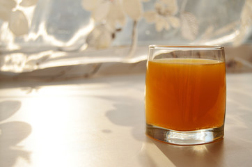 glass with buckthorn juice on a sunny windowsill view from the side