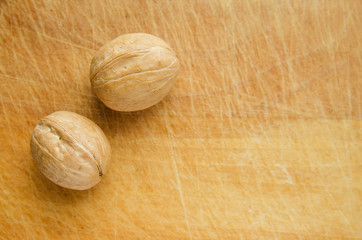 two walnuts on vintage wooden cutboard with knife marks. copy space