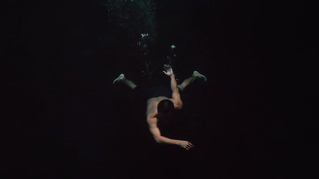Mayan Man diving into deep dark cave water slow motion underwater