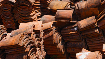 Old clay brown tile. Stacked in even rows. clay shards from an old house roof in the sunlight. classic roof covering