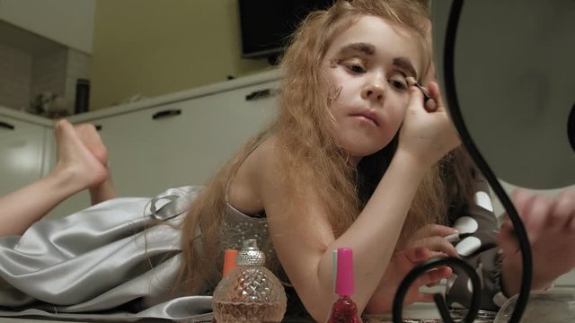 Cheerful child with sister in dresses make each other make-up.