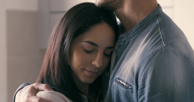 Authentic close up shot of a young man is giving an effective hug and tender kiss to his fiance or wife as a sign of love and support. Concept: family, marriage, couple in love, romance, authenticity