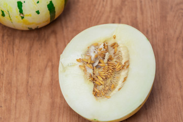 Melon fruit (Cucumis mello L.) halved on a woody background
