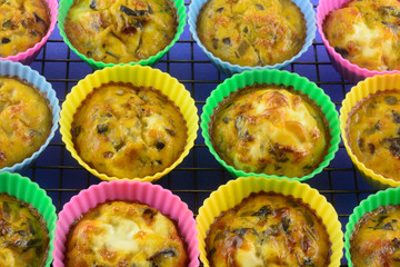 Warm baked scrambled egg cups with chopped mushrooms, bell peppers and onions in silicone muffin cups on cooling rack