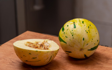 Melon fruit (Cucumis mello L.) halved on a woody background