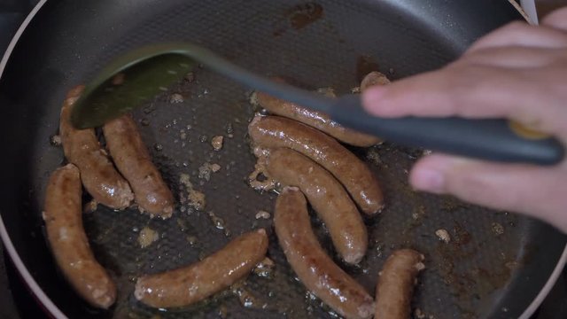 Grill Tongs flipping Sausages on a sizzling hot grill plate