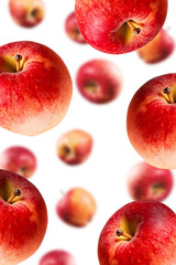 Large ripe red apples falling from top to bottom. Open composition. Close-up. Isolated on white background. Blurred perspective.