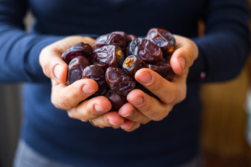 Date fruites, dates or sweet Iranian hurma. Natural organic dieting dessert food. Vegan meal. Woman hands.