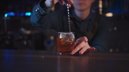 bartender preparing traditional old fashioned cocktail with whiskey and orange