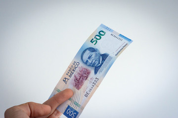 Hand holding mexican peso of 500