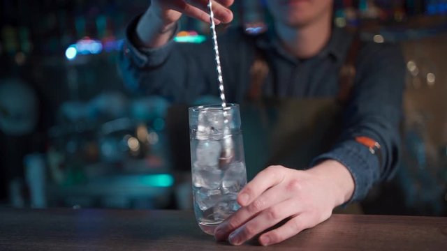 bartender mixing modern gin tonic cocktail with ice