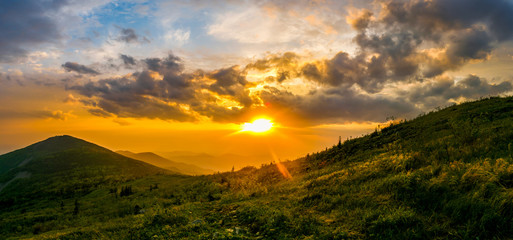 Naklejka na ściany i meble Beautiful landscape. Bright colorful sunset opening from the top of the mountain in the summer. Storm clouds during sunset. relax
