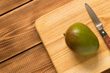 Mango fruit and a knife on a wooden table. Close up.