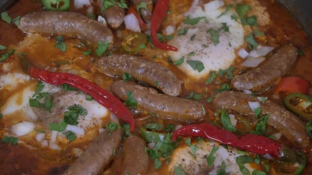 Shakshouka or shakshuka is a North African Jewish origin dish of eggs poached in a sauce of tomatoes, chili peppers, and onions, often spiced with cumin.