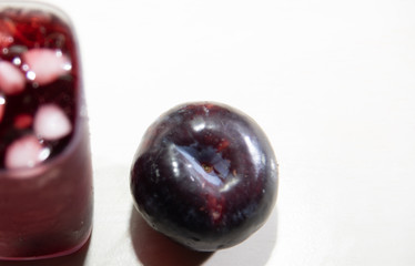 Plum juice (Prunus sp.) Served in a glass with ice and fresh fruits