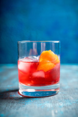 Red traditional old fashioned cocktail with orange zest on the rustic background. Selective focus. Shallow depth of field.