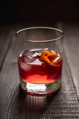 Red traditional old fashioned cocktail with orange zest on the rustic background. Selective focus. Shallow depth of field.