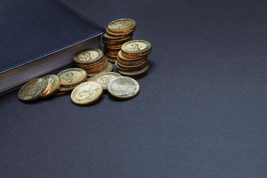 Close view of a stack of coins and a notebook on black background