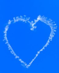A love heart shape made with smoke from a sky writing airplane against a blue sky