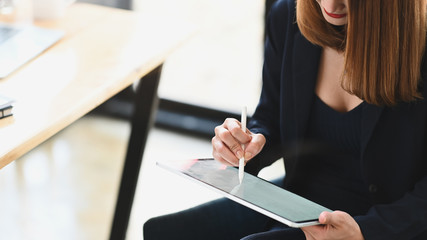 Cropped shot sexy businesswoman holding a computer tablet and stylus pen while sitting at the...