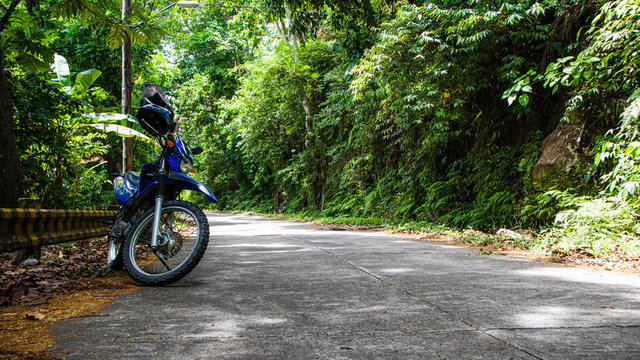 A motorcycle along the side of a tropical jungle road in the Philippines.