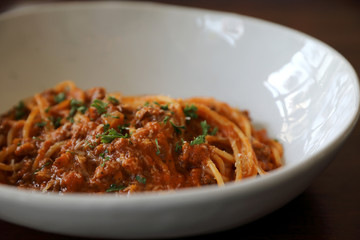spaghetti Bolognese with minced beef and tomato sauce garnished with parmesan cheese and basil , Italian food