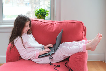 Preteen girl enjoyes homeschooling or video call in comfy pajama and cozy sofa chair. Remote...