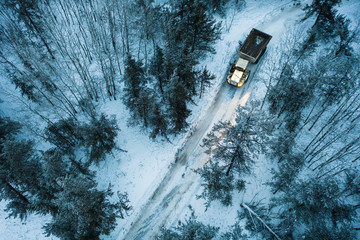 A rock truck travels down a tight path in the scenic winter forest in northern Canada.