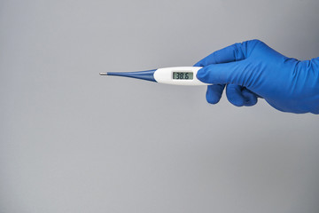 hand in blue glove holds thermometer high temperature