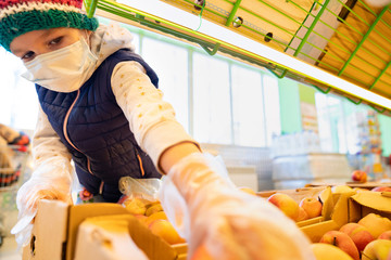 kid girl in medical mask, gloves buys apples