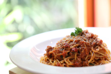 spaghetti Bolognese with minced beef and tomato sauce garnished with parmesan cheese and basil , Italian food