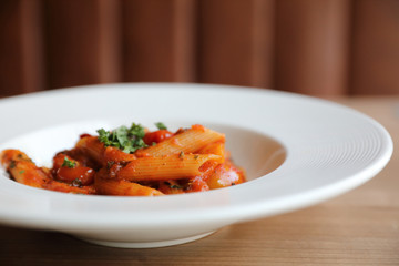 Penne arrabiata pasta tomato sauce with spices italian food on wood background