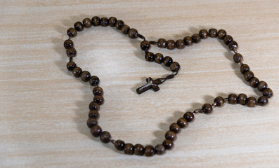 Rosary and crucifix symbols of Catholicism on light wooden background
