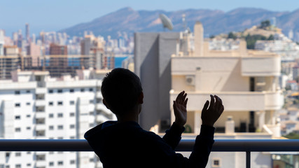 Child applauding medical staff from their balcony. People in Spain clapping gratitude on balconies and windows in support of health workers, doctors and nurses during the Coronavirus pandemic
