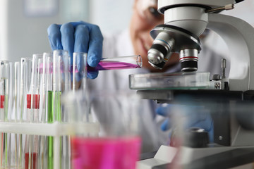 Close-up of professional chemist examining drug sample. Lab researcher investigating coloured...