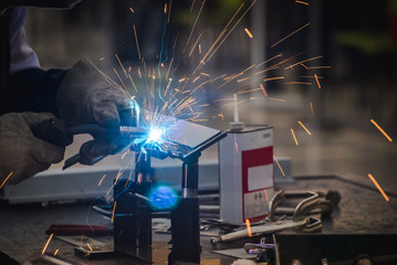 The welder is welding the metal parts in the automobile assembly plant and practicing the skills of the welder in industrial plants.