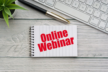 ONLINE WEBINAR text with decorative flower, fountain pen, keyboard and notepad on wooden background. Business and technology concept