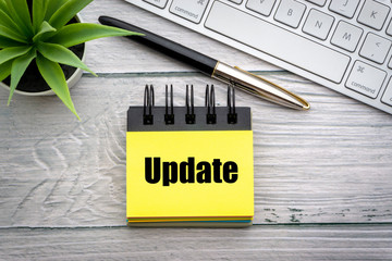 UPDATE text with decorative flower, fountain pen, keyboard and notepad on wooden background....