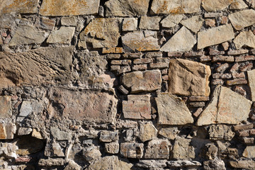 stones of different sizes lie on each other. The wall is made of stone.