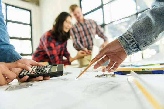 One of the architects or a group of engineers is meeting, working, and pointing to the drawings in the office to talk. Engineering tools and construction concepts Engineering 