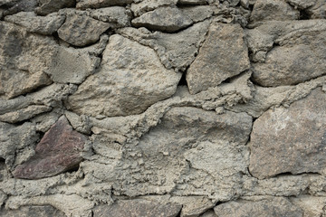 old wall, stones of different sizes lie on each other cement between them.