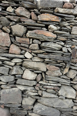 Wall made of natural stone. The texture of the stones of different sizes and shapes that lie on top of each other.